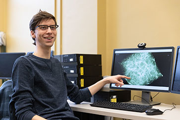 A PNW student points to a visualization on a computer