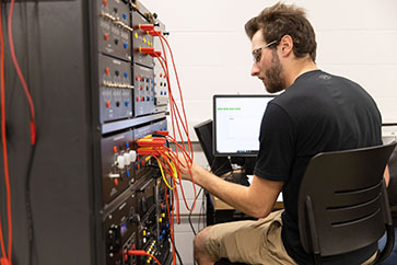 A student plugs wires into a box