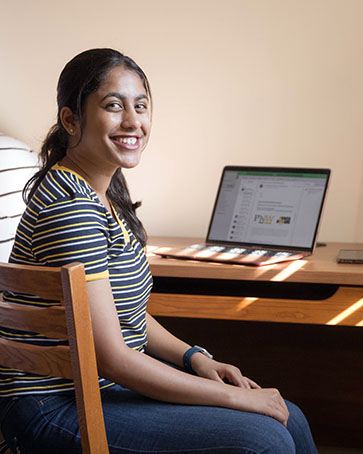 A PNW student sits at a desk in her dorm room.